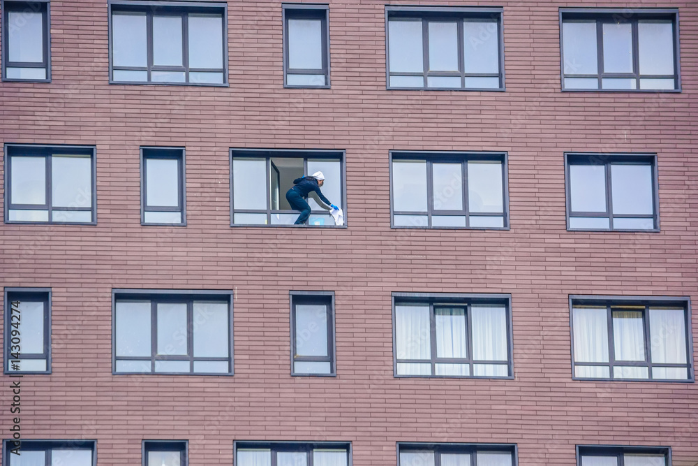 Woman washes window of modern brick building