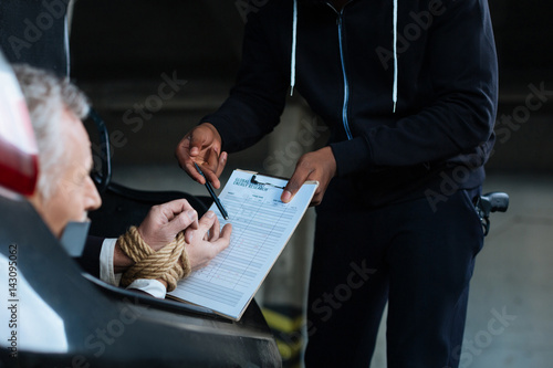 Fotografija Unhappy senior man being forced to sign the document