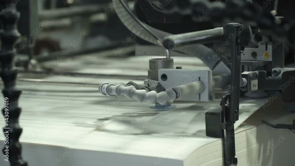 Vacuum sheet feeder supplies individual sheets of paper into printing press from the pile of paper. Related to machinery, technology of printing. Extreme closeup Vacuum sheet feeder supplies individual sheets of paper into printing press from the pile of paper. Related to machinery, technology of printing. Extreme closeup
