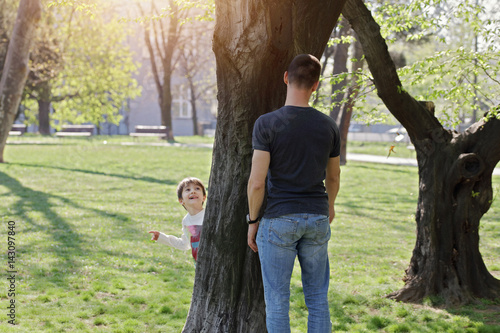 Foto Father and son playing hide and seek in park