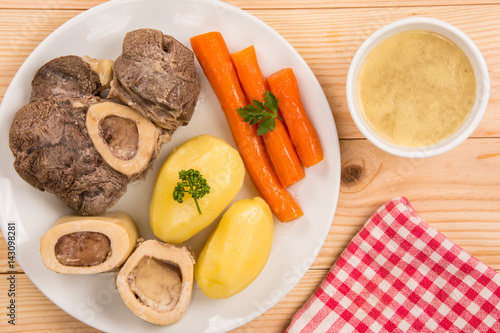High angle view of a pot au feu, a french beef stew on a white plate and wooden background