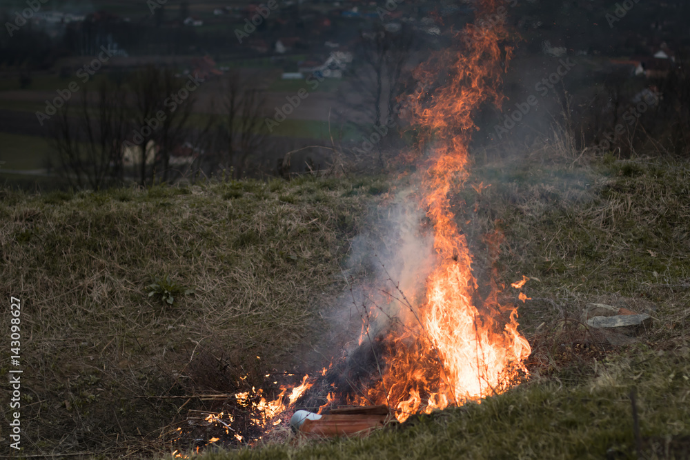 Big fire in countryside field on mountains background. Work in the garden. Farmer raking burning dried branches. Spring time Big fire in countryside field on mountains background. Work in the garden. Farmer raking burning dried branches. Spring time
