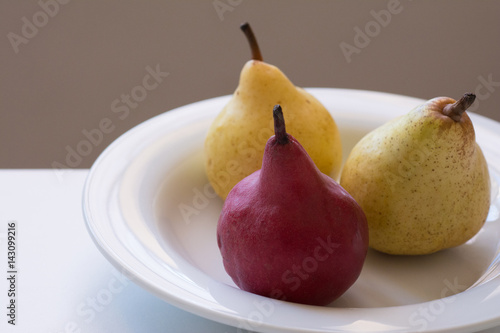 against the light view of a closeup of three organic pears in a white plate