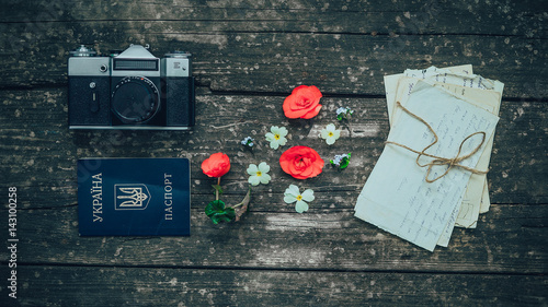 Retro camera with the passport and old letters and flowers on the background of wooden boards. Concept: Old times. photo