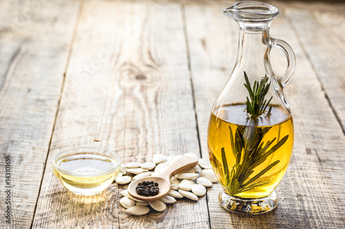 oil in carafe with pepitas and rosemary on wooden background mock-up
