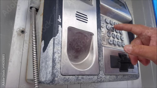 Man dialing a pay public pay phone photo