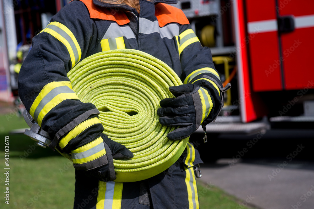 Fototapeta premium Feuerwehrmann trägt einen Schlauch