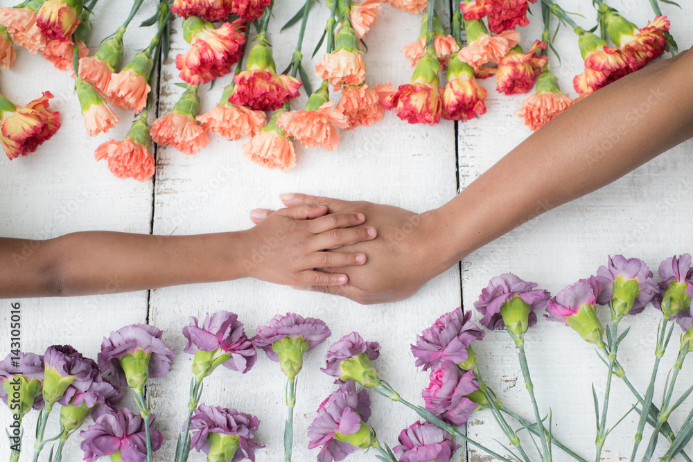 Mothers Day - Mom and Daughter - holding hands and flower background.Love Concept