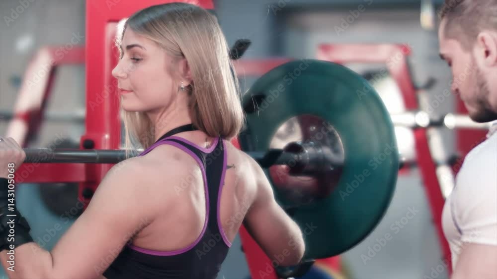 Woman lifting barbell with trainer watching her at the gym Woman lifting barbell with trainer watching her at the gym