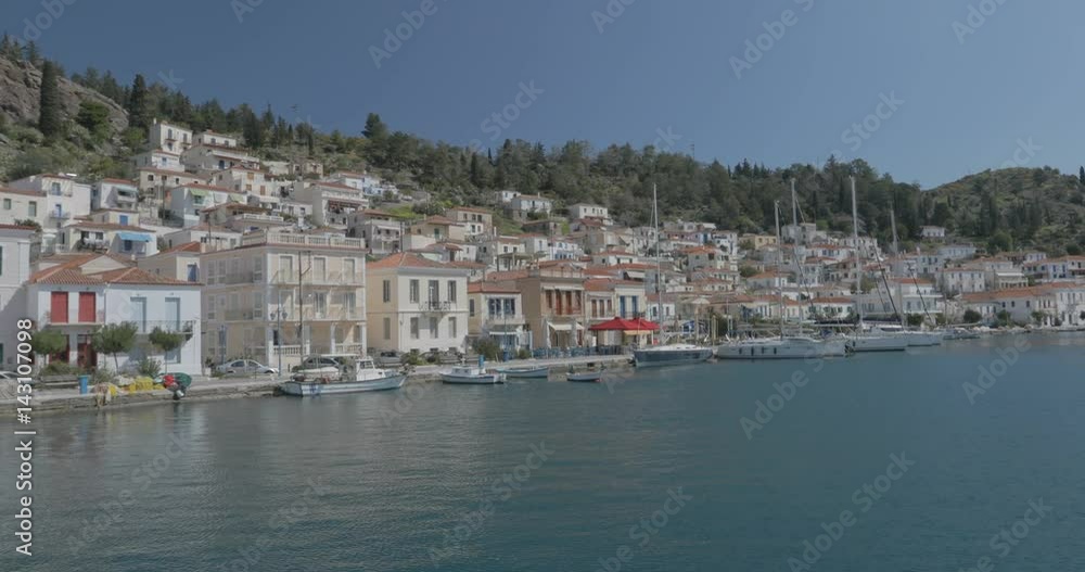 Entering marina of Greek island Poros. Yachts are parked in front of villas at the seafront. Entering marina of Greek island Poros. Yachts are parked in front of villas at the seafront.