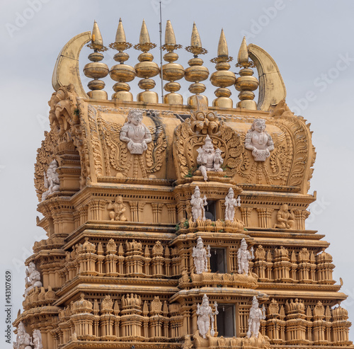 Nanjangud, India - October 26, 2013: Focus on top and elaborately decorated Kalasam of the main Gopuram of Sri Srikanteshware temple in Ganjangud, Karnataka State. Golden decoration, white statues.