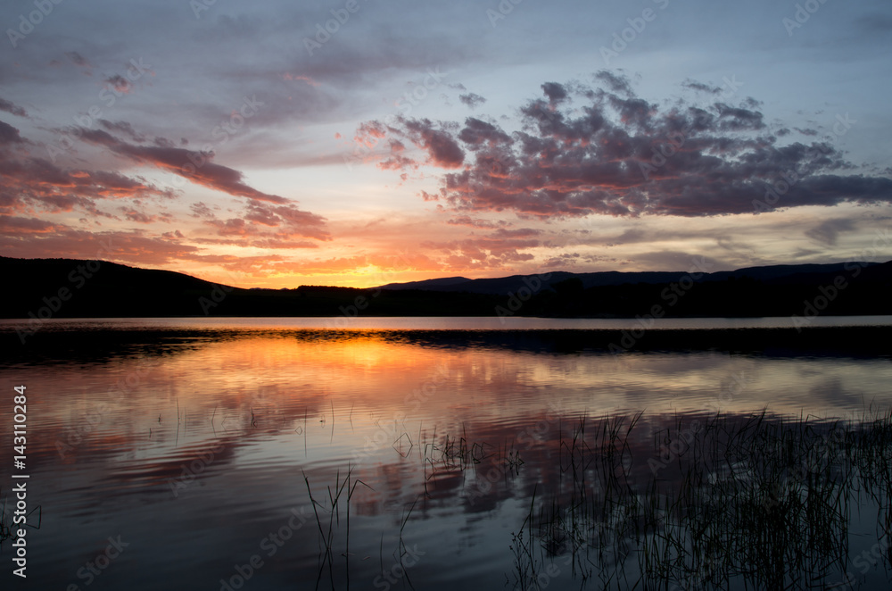 Fototapeta premium Sunset over lake with reflection orange and purple