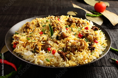 Overhead view=-Homemade delicious mutton dum biriyani or pilaf served in cast iron cookware.