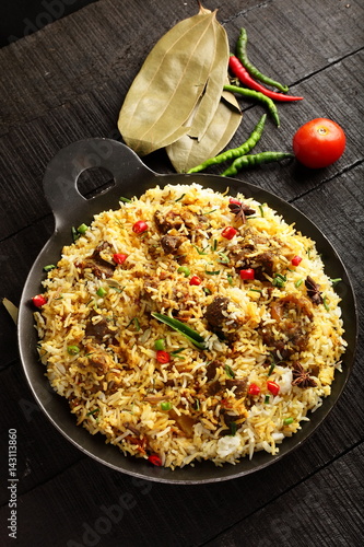 Top view-Homemade delicious mutton dum biriyani or pilaf served in cast iron cookware.