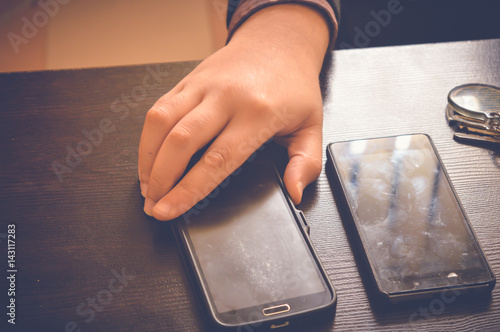 hand on mobile on wooden table with view of another smartphone, business background photo