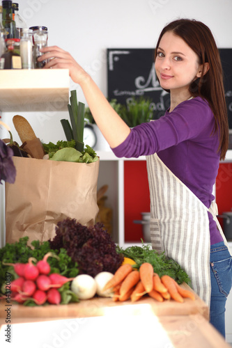 Young woman standing in her kitchen near desk