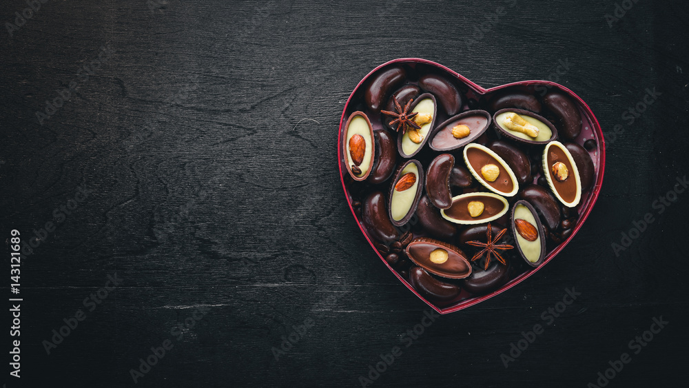 Chocolate box in the form of heart. On a black background Wooden. Top view. Chocolate box in the form of heart. On a black background Wooden. Top view.