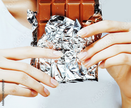 woman eating chocolate, close up hands with manicure french nails holding candy, beautiful fingers, lifestyle concept photo