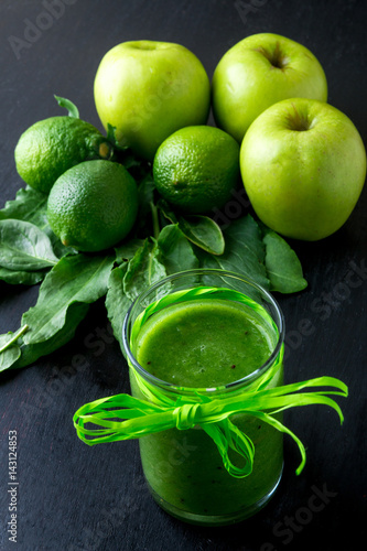 Green smoothie near ingredients for it on black wooden background. Apple, lime, spinach, kiwi. Detox. Healthy drink