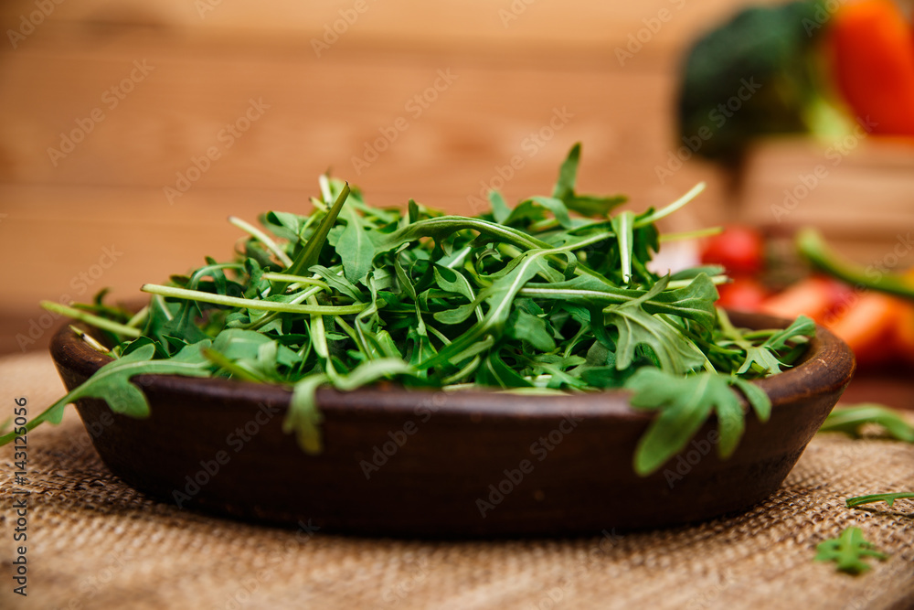Arugula leaves in bowl. Fresh salad. Natural raw vegetables. Organic bio food on rustic wooden table. Arugula leaves in bowl. Fresh salad. Natural raw vegetables. Organic bio food on rustic wooden table.