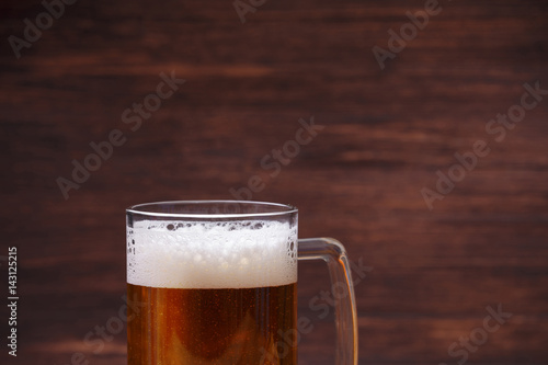 Glass of beer with foam. Mug or pint of ale. Alcohol drink. Pub or bar concept. On rustic wooden background.