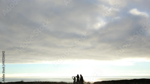 Mother, daughter and grandmother walking and dancing along Mendocino coast during sunset. photo