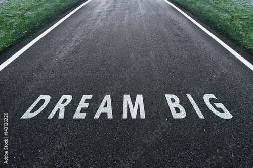 Asphalt road road going straight up with dream big text message. Conceptual business motivation background.