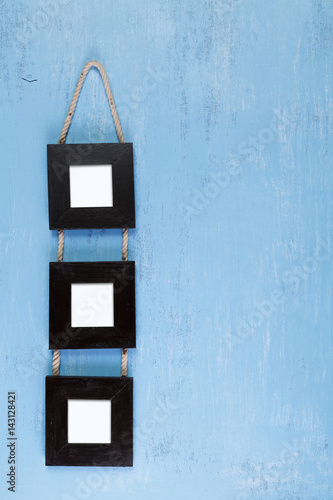 Blank photo frames on blue wood background. Painted scraped wooden board. Grunge plywood texture or pattern. © tanyastock