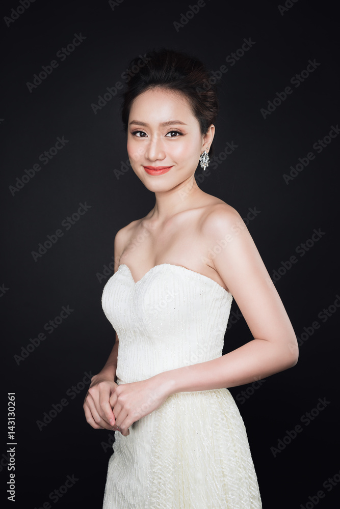 Fashion portrait of beautiful young asian woman in white dress over dark background. Fashion portrait of beautiful young asian woman in white dress over dark background.