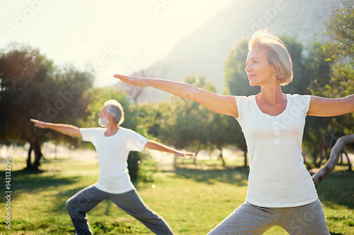 Fototapeta Naklejka Na Ścianę i Meble -  Yoga at park. Senior family couple exercising outdoors. Concept of healthy lifestyle.