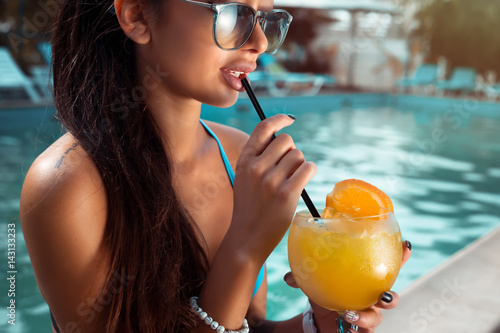 Canvas Print Beautiful brunette woman wearing a blue bikini and jeans shorts, enjoying the pool, summer time