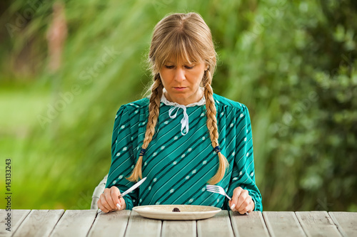 Young lonely woman is having meager meal in times of scarcity.  photo