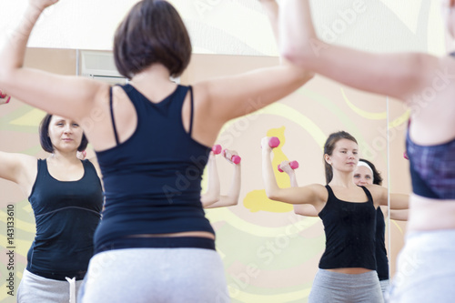Fitness and Sport Concept and Ideas. Four Athletic Caucasian Women Doing Work Out Exercises with Barbells in Gym.