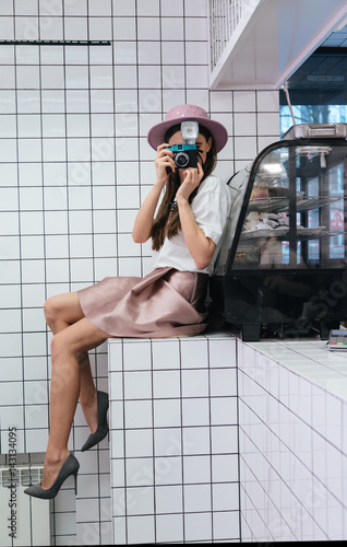 Woman sitting on counter in vafe and taking pictures photo