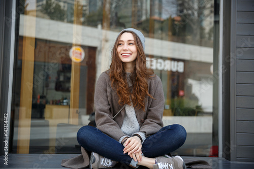 Cheerful attractive young woman sitting outdoors in the city