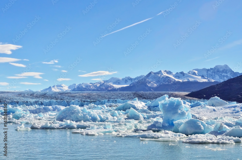 Single blue icebergs and blue sky with white clouds and mountains on the background. Upsala Glacier at Argentino Lake, Los Glaciares National Park, Patagonia, Argentina