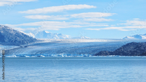 Single blue icebergs and blue sky with white clouds and mountains on the background. Upsala Glacier at Argentino Lake, Los Glaciares National Park, Patagonia, Argentina