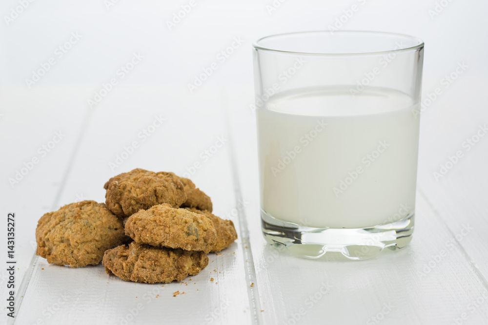 A glass of milk and homemade cookies on white wooden table. A glass of milk and homemade cookies on white wooden table.