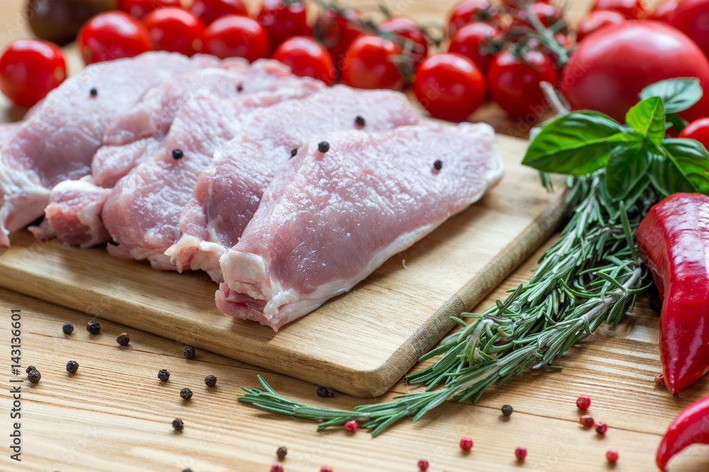 Raw pork on cutting board and vegetables Raw pork on cutting board and vegetables