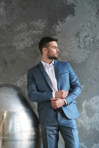 Man in blue suit gray background with metal armchair
