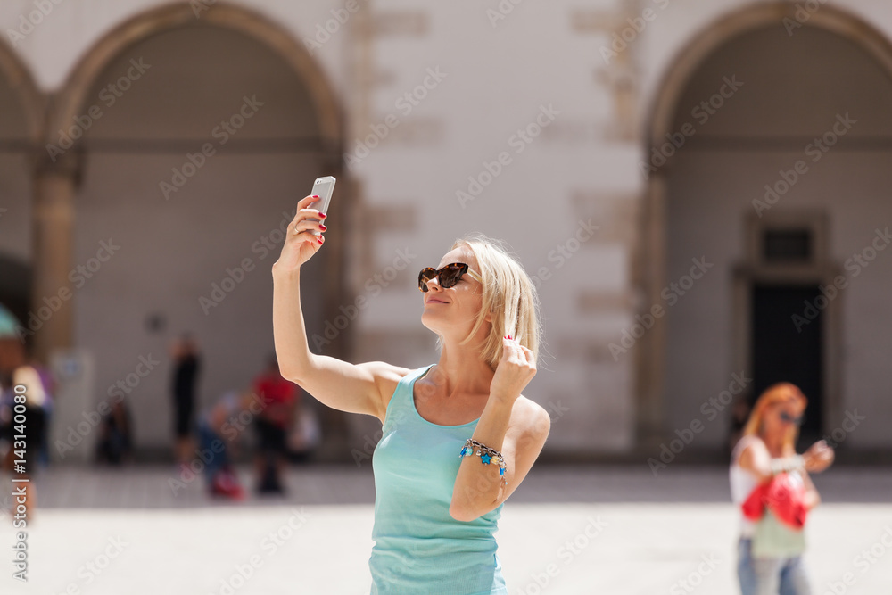 Fototapeta premium Female traveler on the background of Arcades in Wawel Castle in Cracow. Poland. Renaissance. A woman is photographed on her phone against the background of the castle courtyard