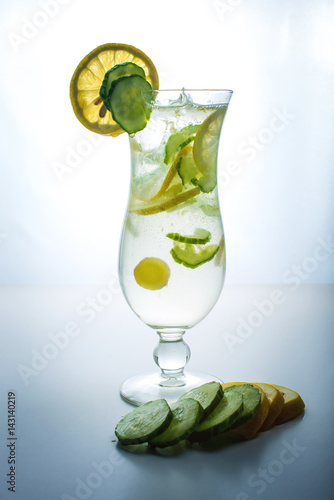 Fruit lemonade in hurricane glass with lemon and cucumber.