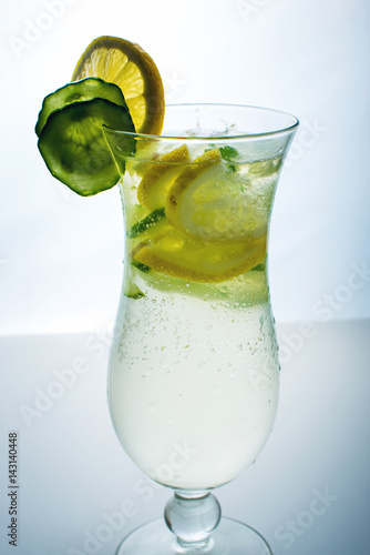 Fruit lemonade in hurricane glass with lemon and cucumber.
