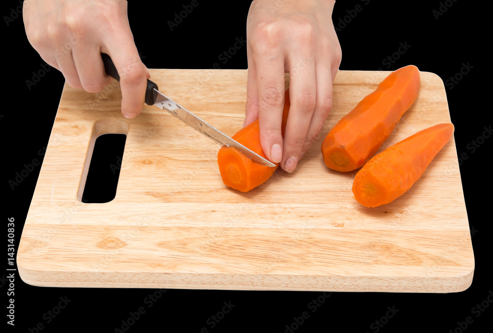 cook cuts carrots on a board on a black background cook cuts carrots on a board on a black background