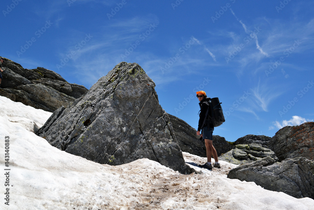 Young guy with glasses traveler, a backpacker traveling through Europe, up into the mountains, the Alps, to a height, the traveler in the mountains