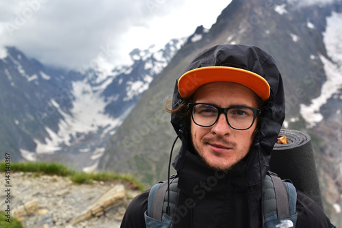 Young guy with glasses traveler, a backpacker traveling through Europe, up into the mountains, the Alps, to a height, the traveler in the mountains © Ксения Ощепкова
