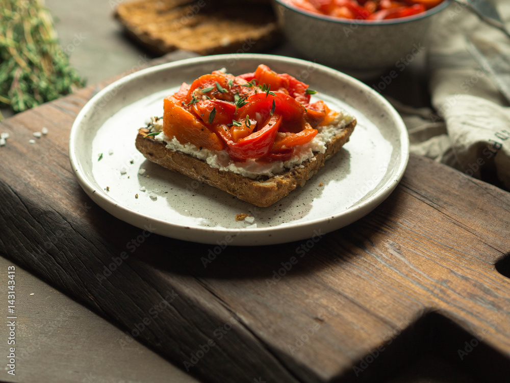 Vegetarian toast with baked pepper and cream cheese on a plate on a wooden board
