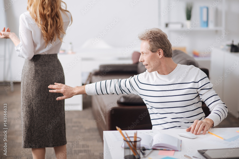 Fototapeta premium Positive aged businessman touching young colleague body at work