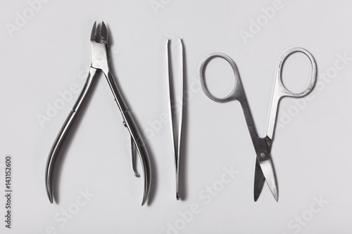 Nail clippers, nail scissors and cosmetic tweezers on white background