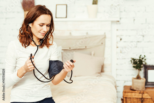 Healthy young woman using tonometer at home photo